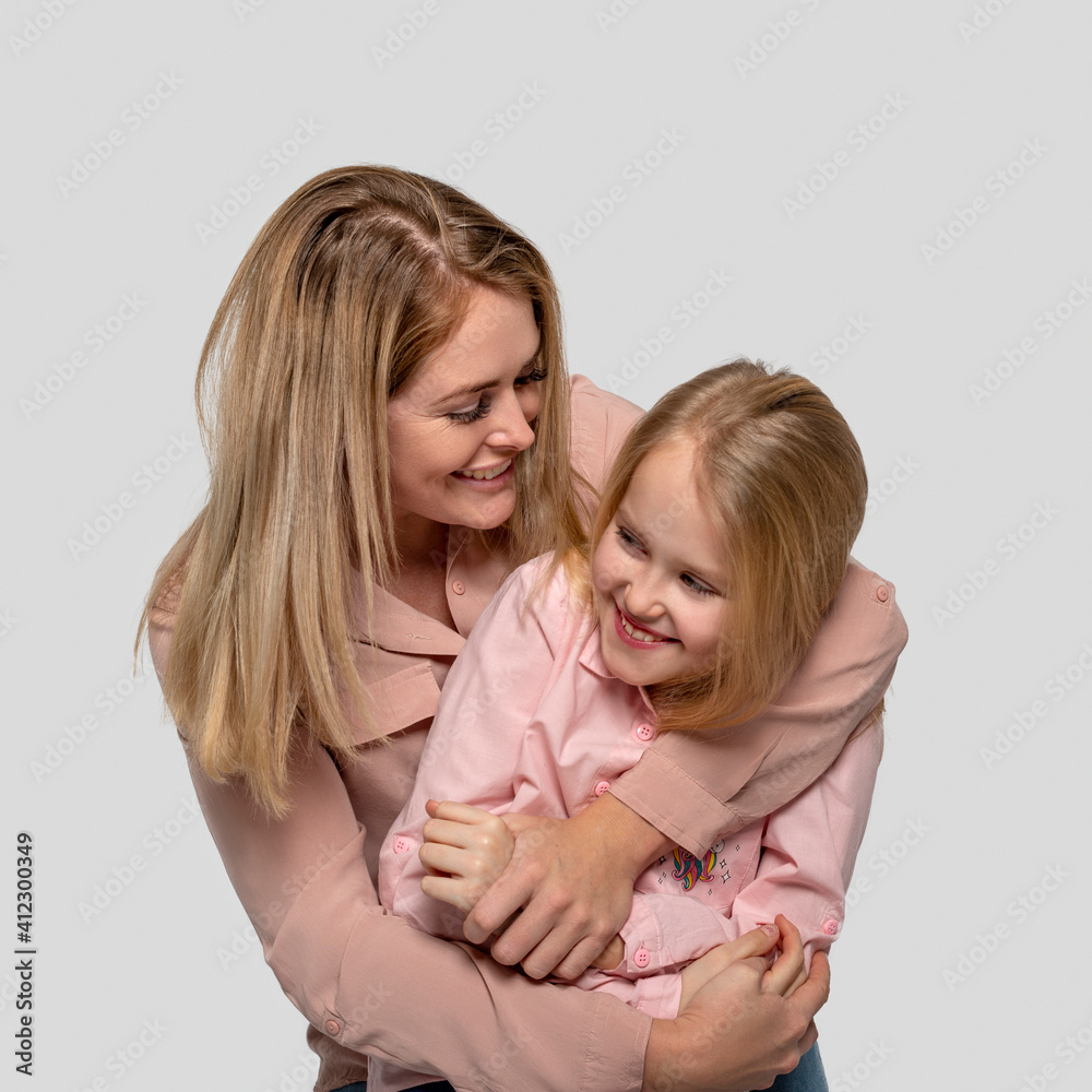 Shot of a happy cheerful mom hugging her little daughter with love against white basckground Shot of a happy cheerful mom hugging her little daughter with love against white basckground