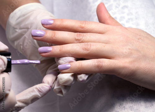 The process of manicure fitting natural nails filing nails coating with colored gel polish and glossy top.