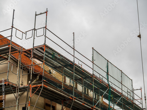 Scaffolding around the house roof, grey sky background