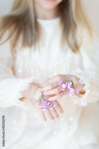 Close-up portrait of smiling little caucasian girl with gypsophila flowers isolated on grey background. Model in studio. Trendy creative idea