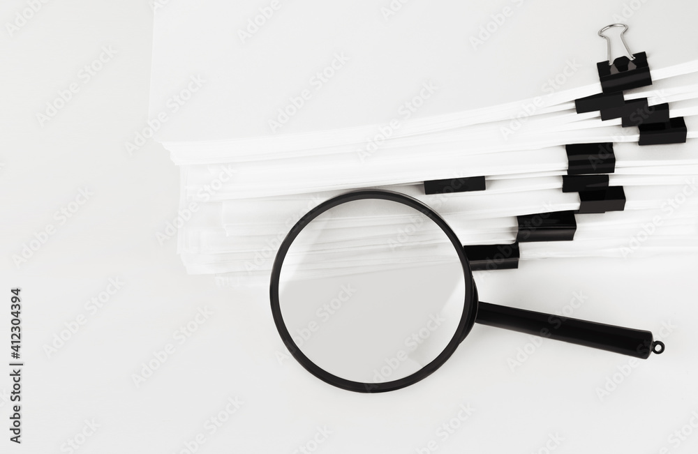Stack of report paper documents with magnifying glass. Concept of business and search. - obrazy, fototapety, plakaty 