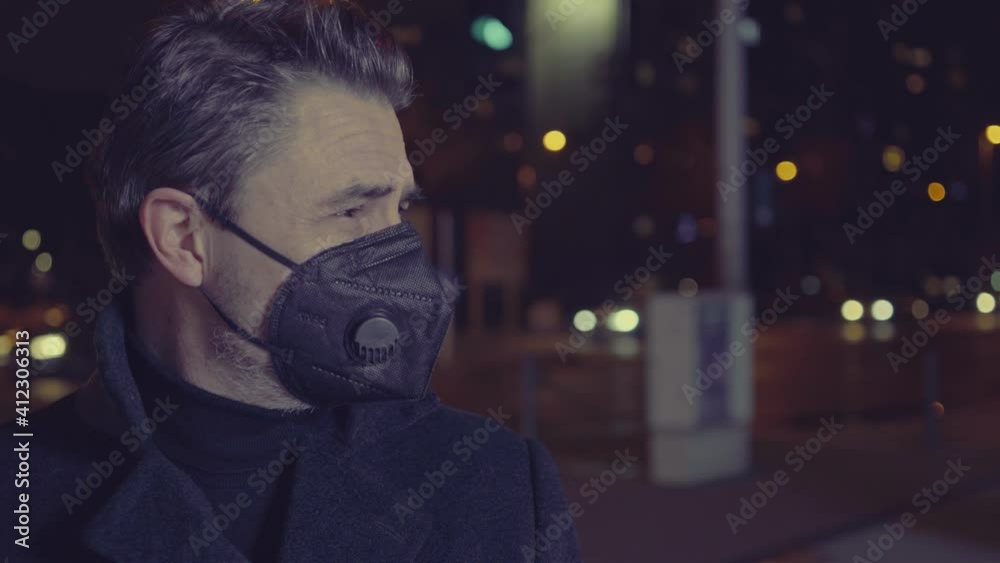 Covid-19 portrait - man in medical face mask on street in Winter. City lights at night. Covid-19 portrait - man in medical face mask on street in Winter. City lights at night.