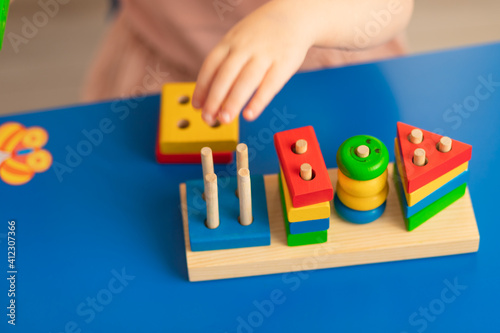 
Children's wooden toy. The child collects the sorter. Educational logic toys for children. Baby hands close up. Montessori games for child development