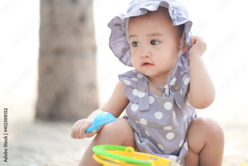 Asian cute baby girl playing on the sand beach on sunny day Asian cute baby girl playing on the sand beach on sunny day
