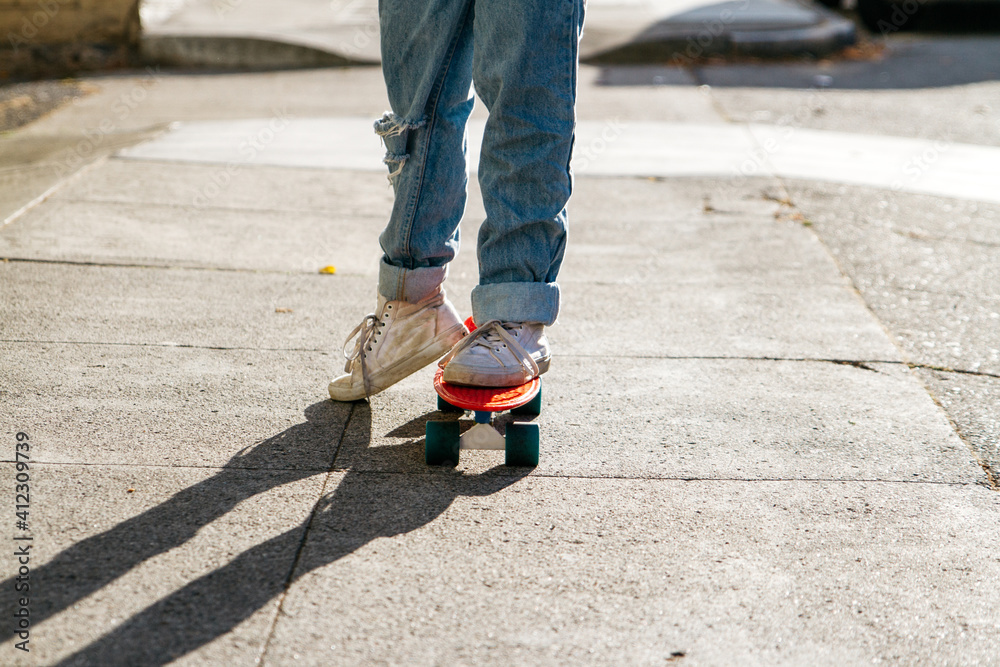 young woman legs in ripped jeans while riding skateboard on sidewalk young woman legs in ripped jeans while riding skateboard on sidewalk