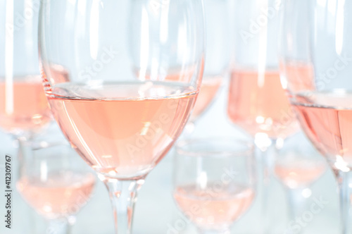blurred background of many different glasses with rose wine