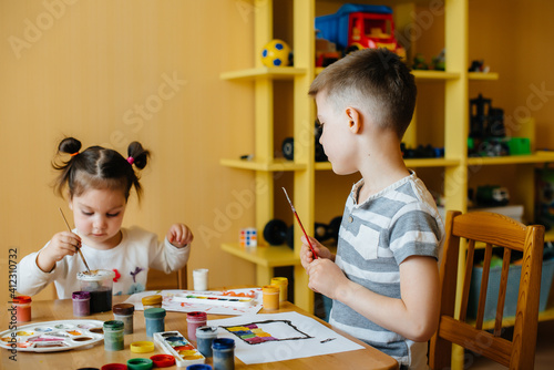 A boy and a girl play together and paint. Recreation and entertainment. Stay at home