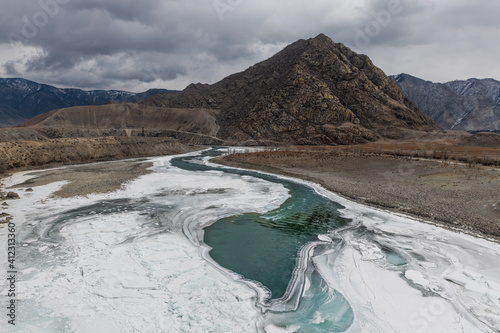 Stunning landscape of Altai mountains and river Katun partly covered by ice in winter