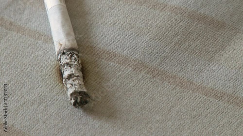 Close up burning cigarette with smoke in the bedroom on the bed leads to a fire. The process of developing a fire from a cigarette. Fire hazard concept of a house from smoking 4k