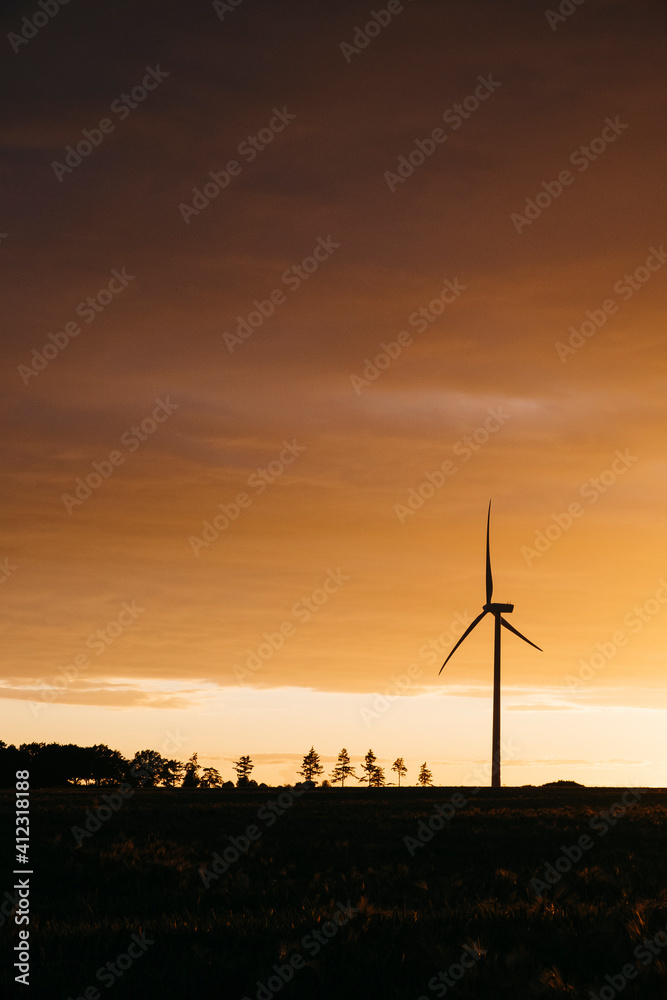 Wind turbine silhouetted against orange cloud at sunset. Norfolk, UK. Wind turbine silhouetted against orange cloud at sunset. Norfolk, UK.