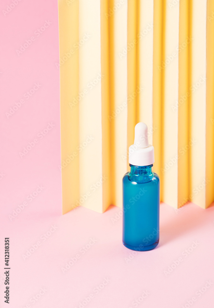 Hyaluronic acid serum generic bottle treatment on pink geometric background with yellow paper fan Hyaluronic acid serum generic bottle treatment on pink geometric background with yellow paper fan