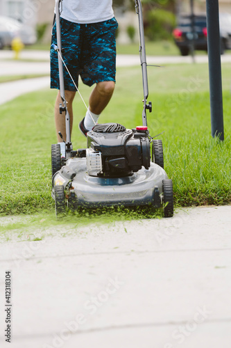 Teenage boy mowing the lawn