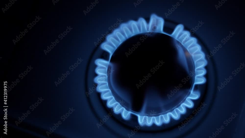 Kitchen burner turning on. Stove top burner igniting into a blue cooking flame. Natural gas inflammation, close up.