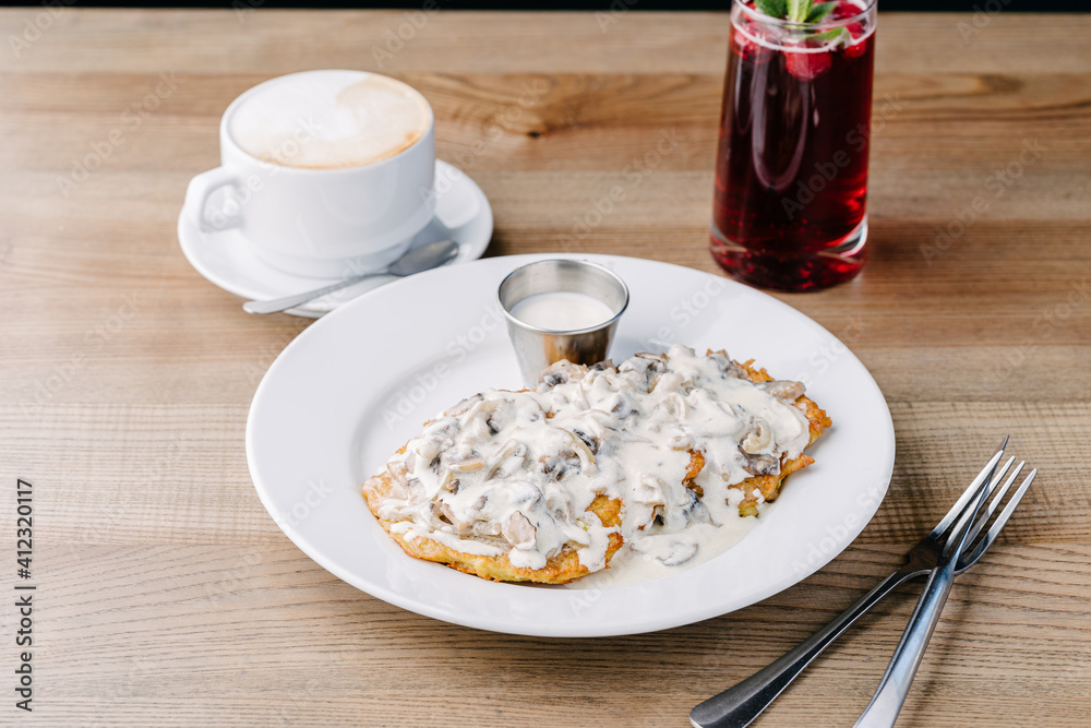 Potato pancakes with mushroom sauce. On a table in cafe Potato pancakes with mushroom sauce. On a table in cafe