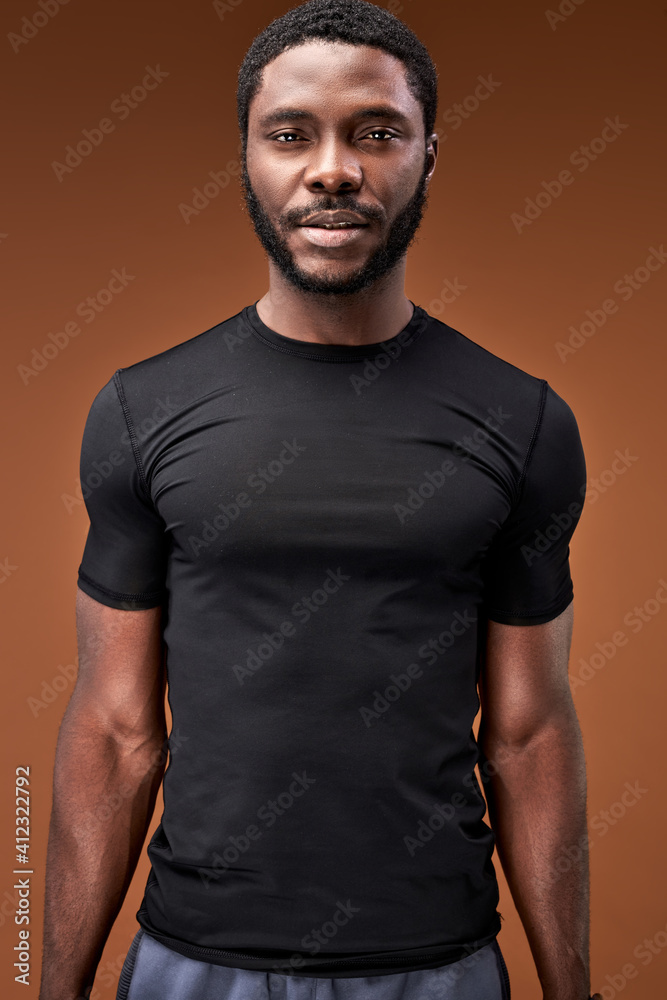 confident sportsman looking at camera isolated on brown background, handsome bearded male in black sportive t-shirt confident sportsman looking at camera isolated on brown background, handsome bearded male in black sportive t-shirt