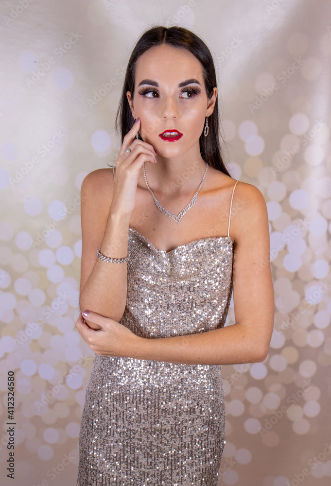A sexy elegant woman wearing a silver glittery party dress with long brown  hair and red