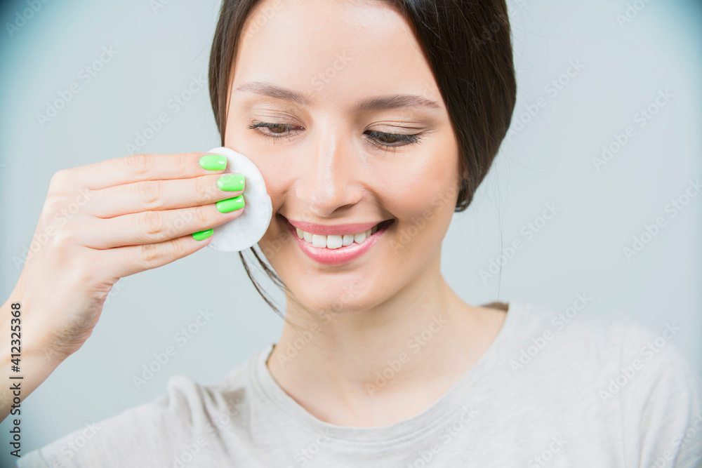 Beautiful brunette woman with a sponge, clean perfect fresh skin using cotton pad skin care concept. Isolated on a white Beautiful brunette woman with a sponge, clean perfect fresh skin using cotton pad skin care concept. Isolated on a white