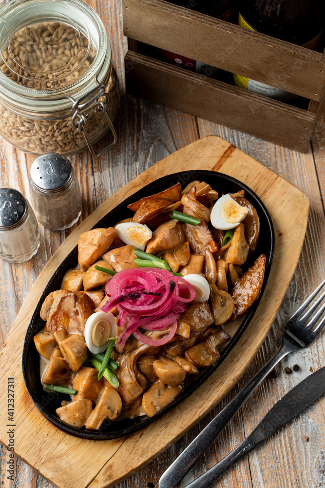 German slow stew with potato, mushrooms and onion, covered with gravy on wooden tray German slow stew with potato, mushrooms and onion, covered with gravy on wooden tray