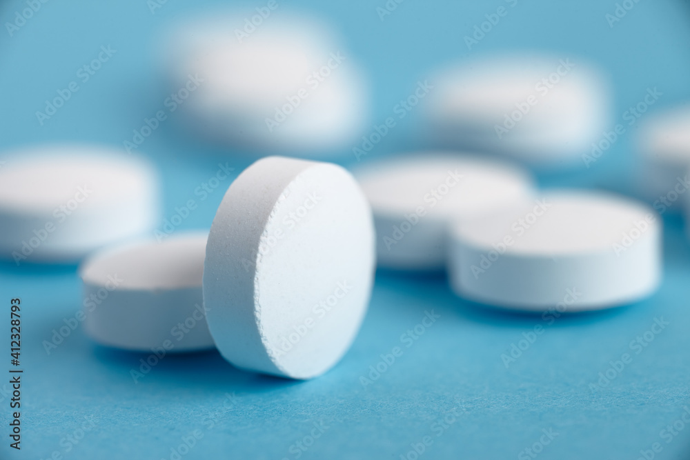 Closeup of white pills on a blue background. Heap of pills - medical background Closeup of white pills on a blue background. Heap of pills - medical background
