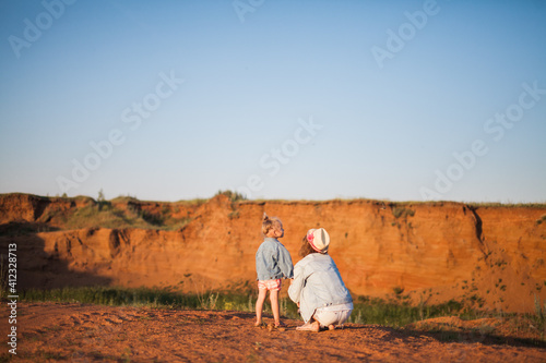 Young mother and her hip daughter looking over a swallow canyon on the sunset on the nice summer eveninf photo