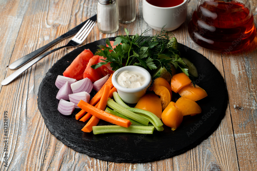 Vegetables platter with tomato, celery, onion and carrot sticks, sauce boat in the centre Vegetables platter with tomato, celery, onion and carrot sticks, sauce boat in the centre