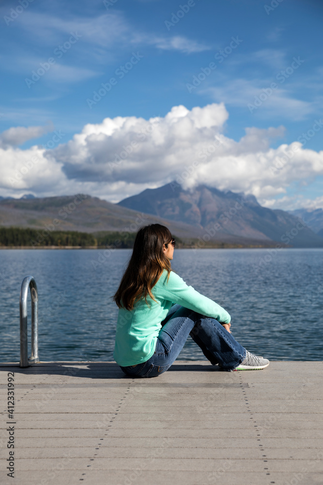 Young Woman Relaxes on the Lake McDonald Pier in Glacier Nationa Young Woman Relaxes on the Lake McDonald Pier in Glacier Nationa