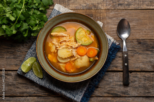 Chicken soup with rice and vegetables on wooden background