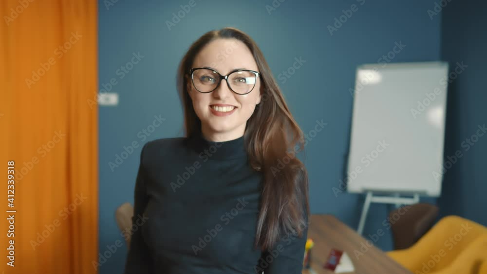 Portrait of a successful female leader in glasses in the office. Close-up woman of European appearance standing in the office, looking at the camera dressed in stylish business clothes. Moving dynamic Portrait of a successful female leader in glasses in the office. Close-up woman of European appearance standing in the office, looking at the camera dressed in stylish business clothes. Moving dynamic