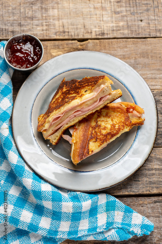 Ham and melted cheese sandwich called Monte Cristo on wooden background