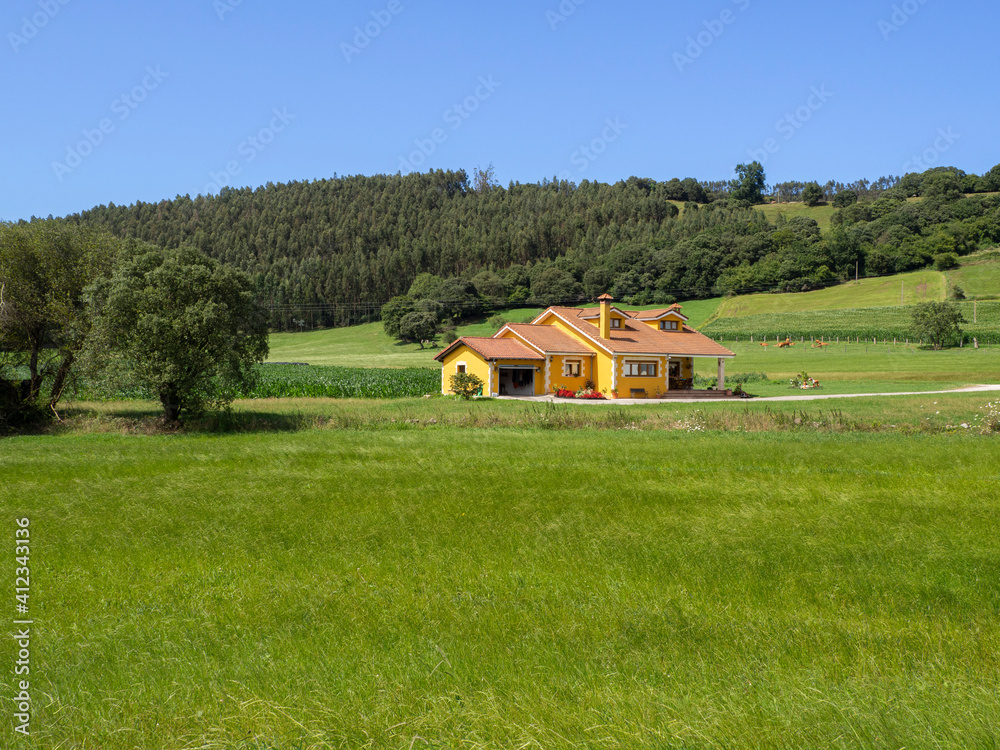 Casa amarilla en enmedio de un campo de césped verde y árboles, verano de 2020 , en Cantabria, España. Casa amarilla en enmedio de un campo de césped verde y árboles, verano de 2020 , en Cantabria, España.
