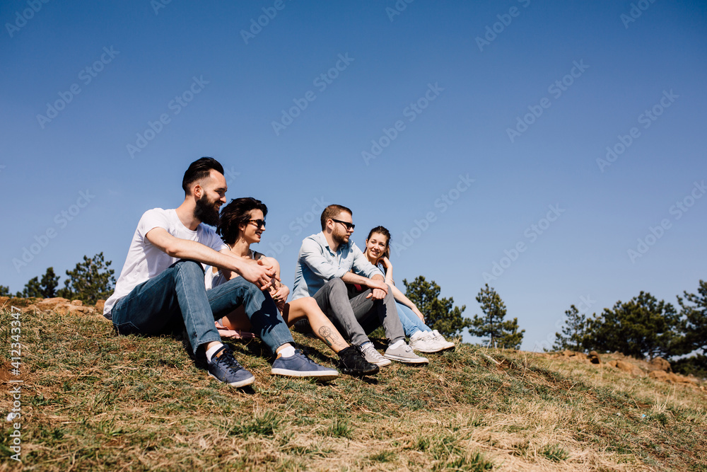 Group of friends sitting on grass and enjoying mountain landscape Group of friends sitting on grass and enjoying mountain landscape
