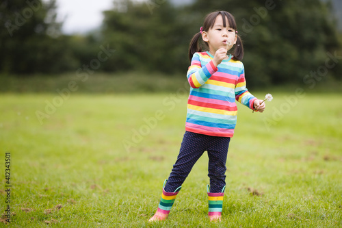 young girl blowing dandelion in the summer garden morning