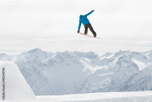 Man doing midair tricks on snowboard while riding in the snowpark