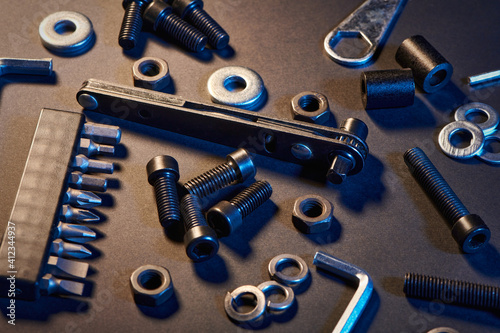 Different screws, nuts, washers, screwdrivers on black background. Hardware tools and metal bolts, nuts, and washers. Fasteners concept and goods for repair.