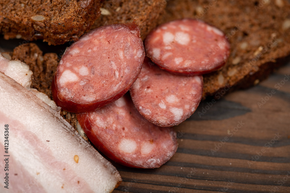 Sandwich with smoked brisket sliced on grain bread and homemade sausage on a wooden cutting board. Sandwich with smoked brisket sliced on grain bread and homemade sausage on a wooden cutting board.