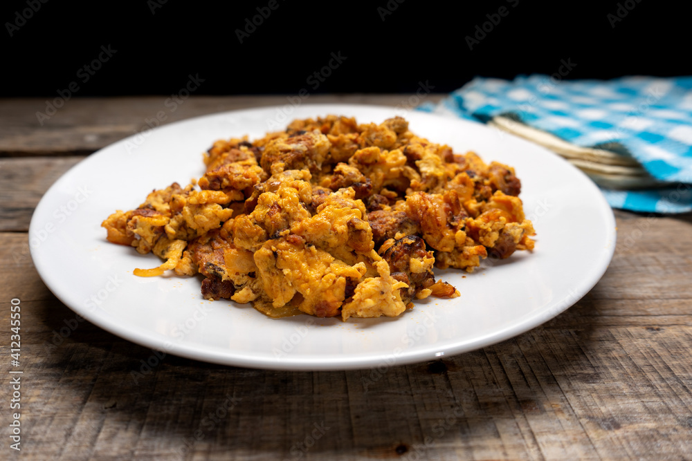Scrambled eggs with chorizo for breakfast on wooden background. Mexican food Scrambled eggs with chorizo for breakfast on wooden background. Mexican food