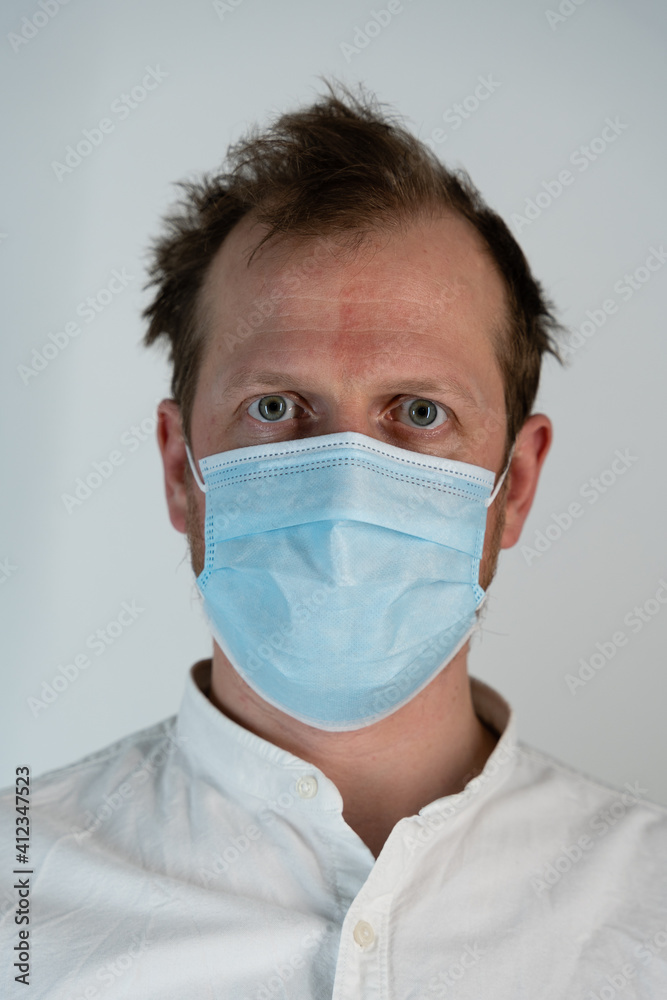 Portrait of a straight man in a white shirt with curly hair and a straight tight look and face mask to protect against covid19, he looks straight Portrait of a straight man in a white shirt with curly hair and a straight tight look and face mask to protect against covid19, he looks straight