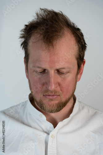 Close up portrait of a man where he is angry looking down and his hair is drilled