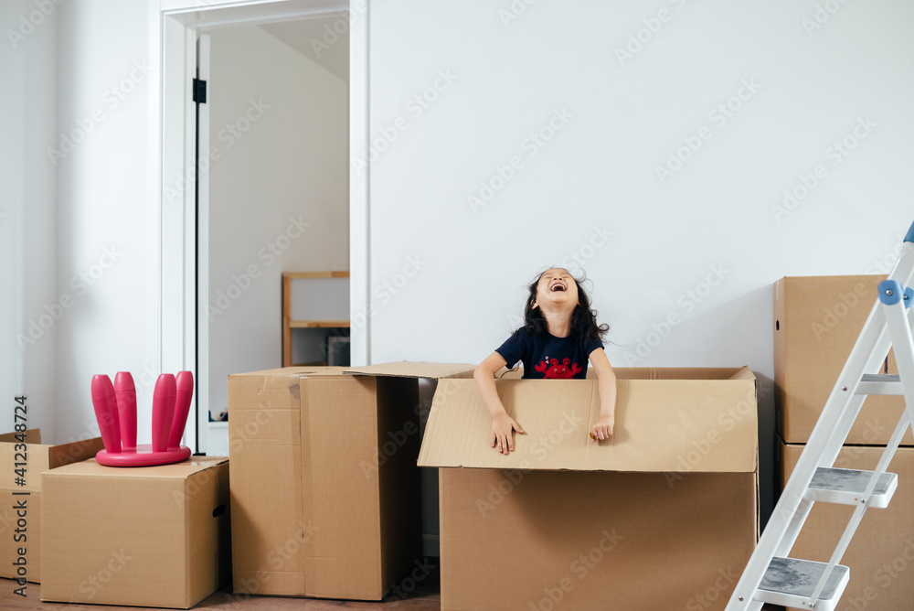Smiling girl playing in cardboard box Smiling girl playing in cardboard box