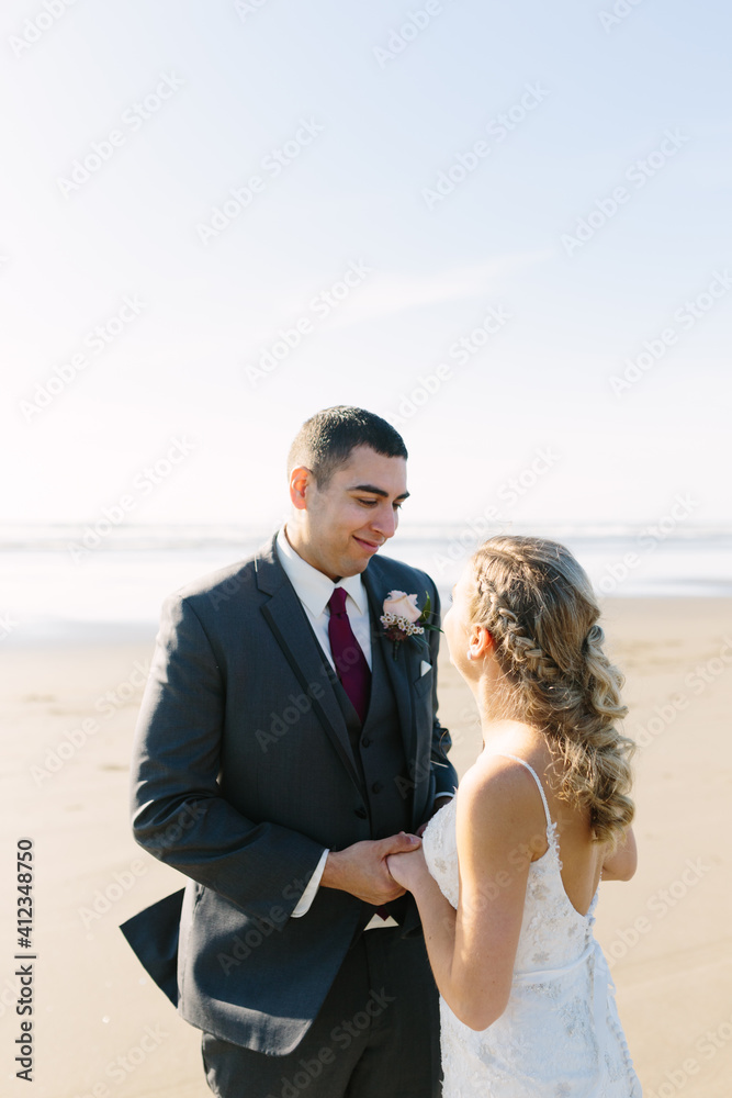 Groom Holding Bride's Hands and Looking into Her Eyese at Beach Groom Holding Bride's Hands and Looking into Her Eyese at Beach