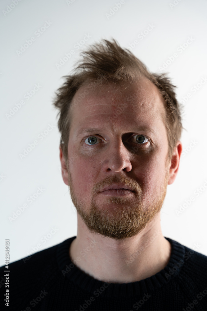 A close up portrait of a serious man on a white background with a very serious face and gaze