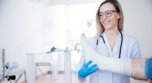 Smiling female doctor bandaging patient s leg. Emergency.
