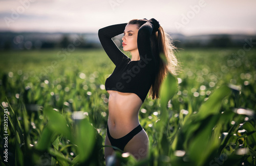 Sensual young woman with a slim figure enjoys a sunny summer day in cornfield