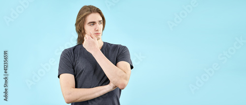 Portrait of an emotional young man in a T shirt posing for the camera isolated on a blue background