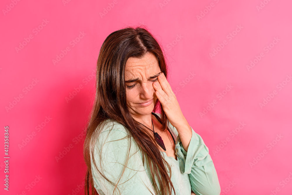 Young 25 year old student girl with headache and body discomfort, isolated on colored background.