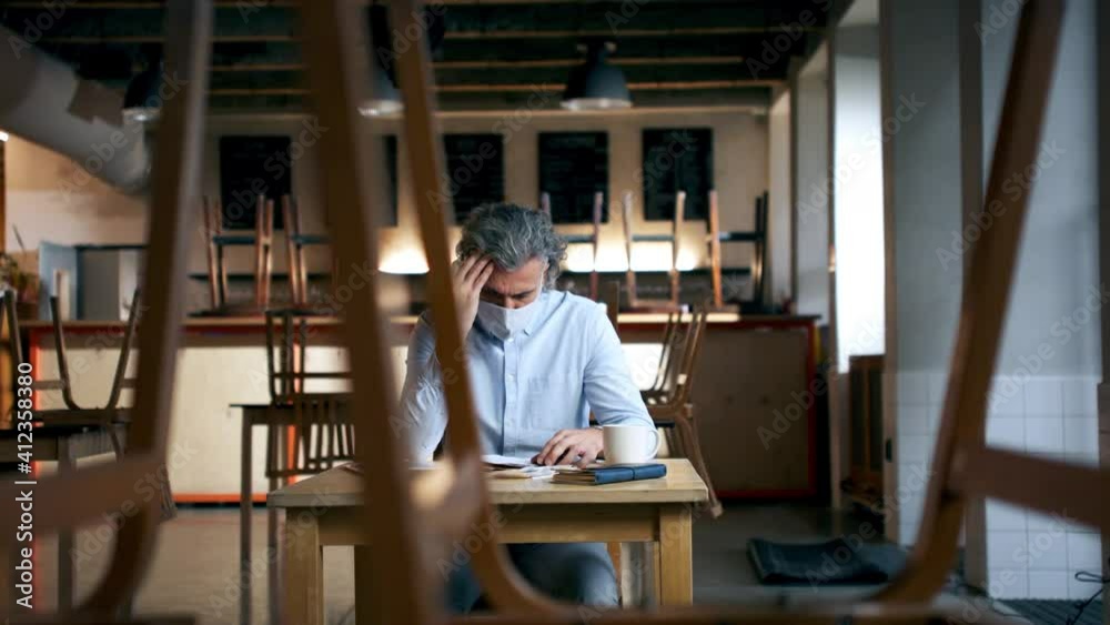 Frustrated owner sitting at table in closed cafe, small business lockdown due to coronavirus. Frustrated owner sitting at table in closed cafe, small business lockdown due to coronavirus.