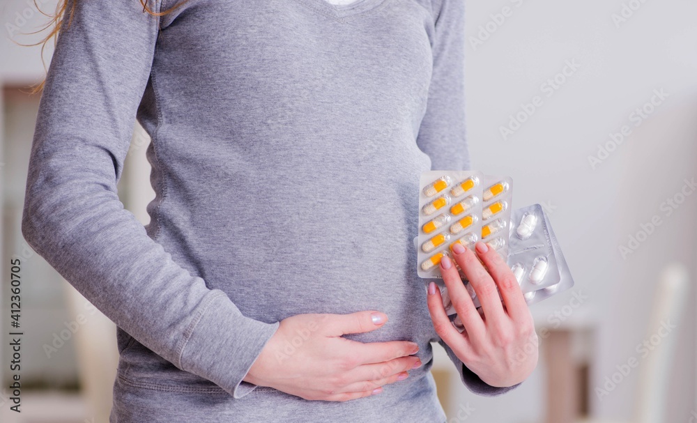 Obraz premium Pregnant woman taking pills during pregnancy