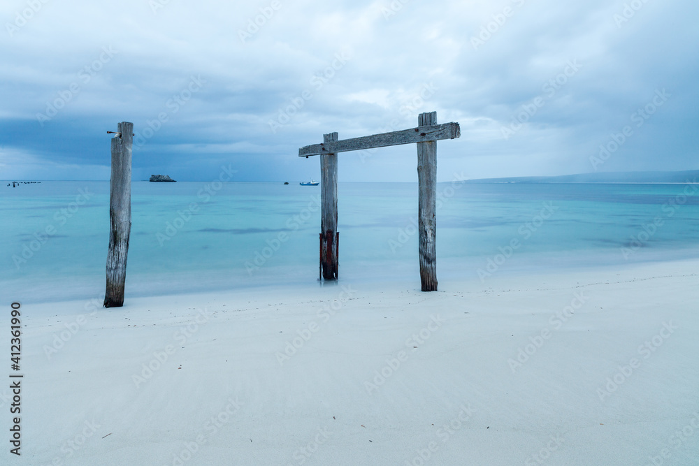 Old worn out wooden pylons on long ago pier