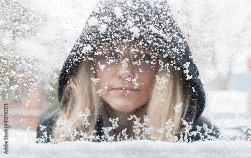 Woman Looks Through Snowy Window photo