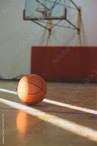 A basketball sits between sunbeams on a basketball court